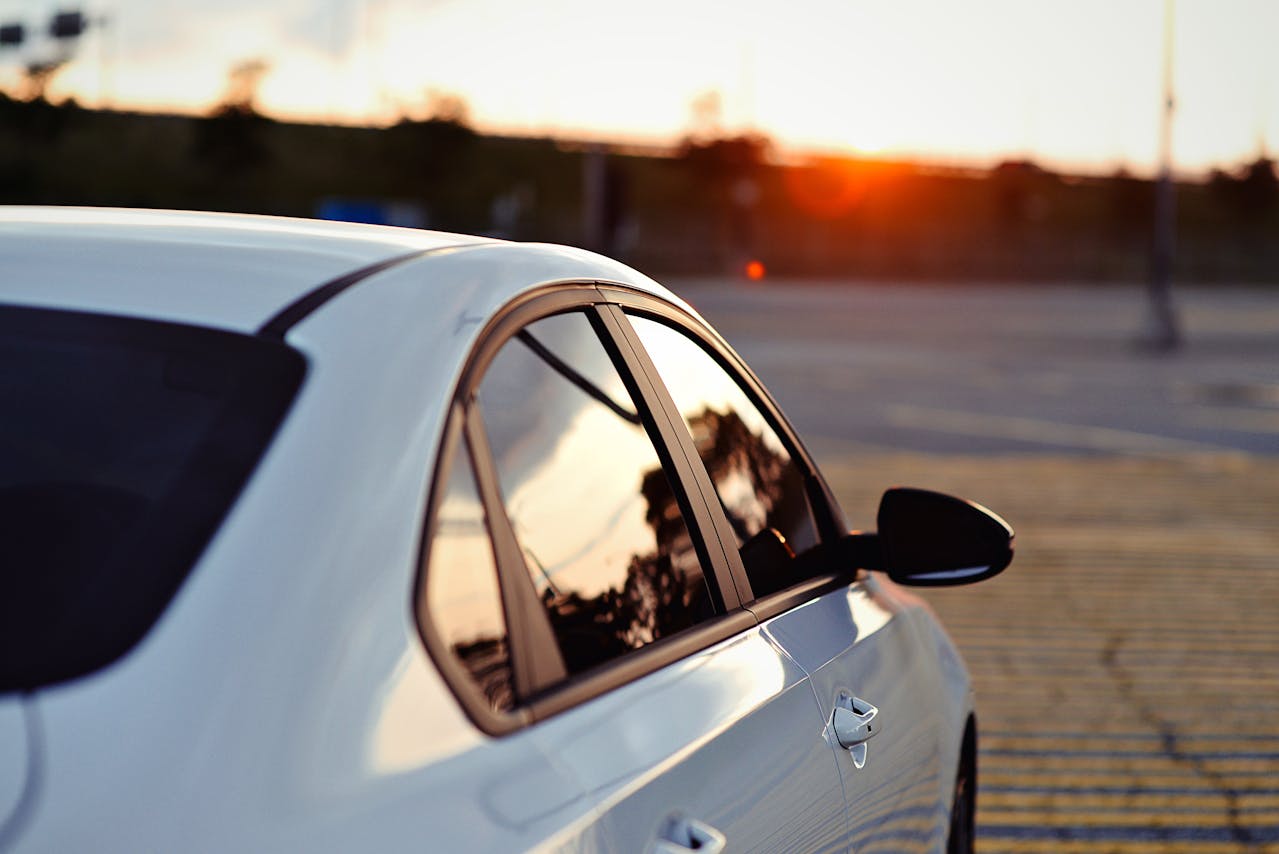 Wie Autotönungsfolien vor Sonne schützen Weißes Auto mit getönten Seitenscheiben bei Sonnenuntergang