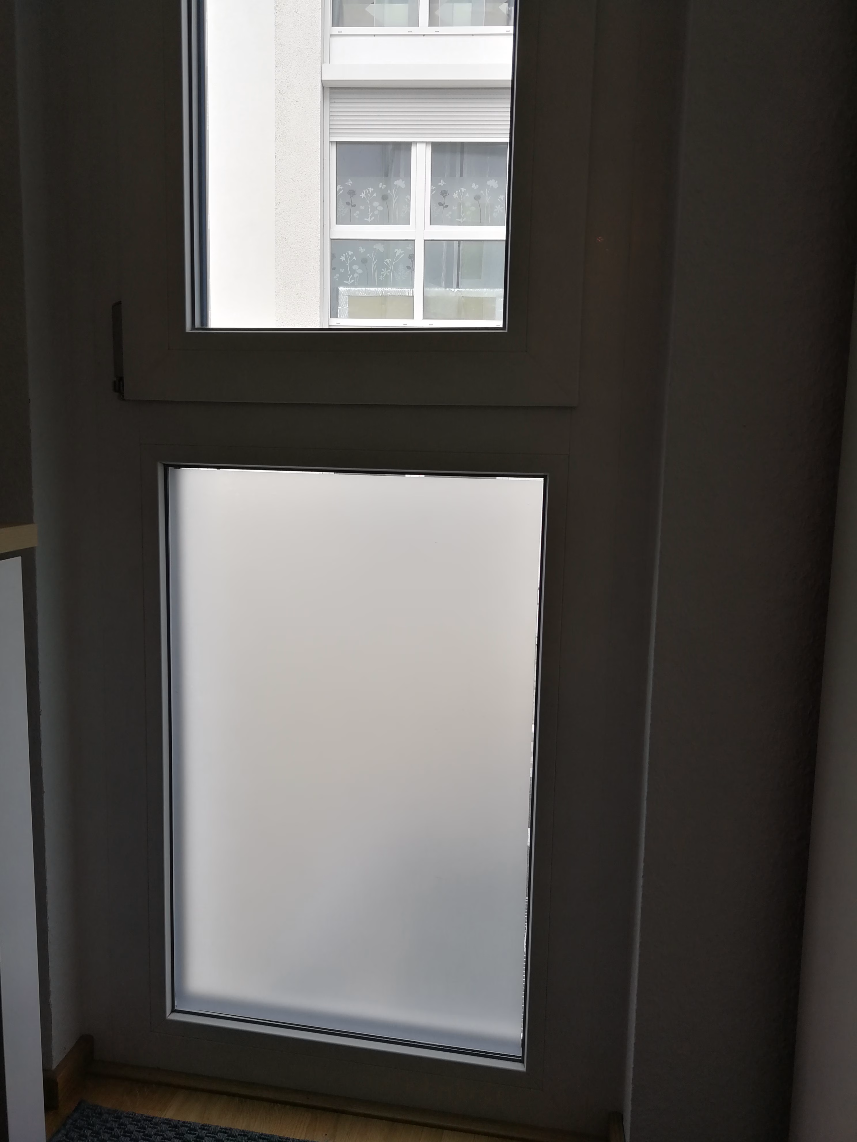 Eine weiß matte, selbsthaftende Sichtschutzfolie auf einem feststehenden Fenster angebracht Eine weiß matte, selbsthaftende Sichtschutzfolie auf einem feststehenden Fenster angebracht