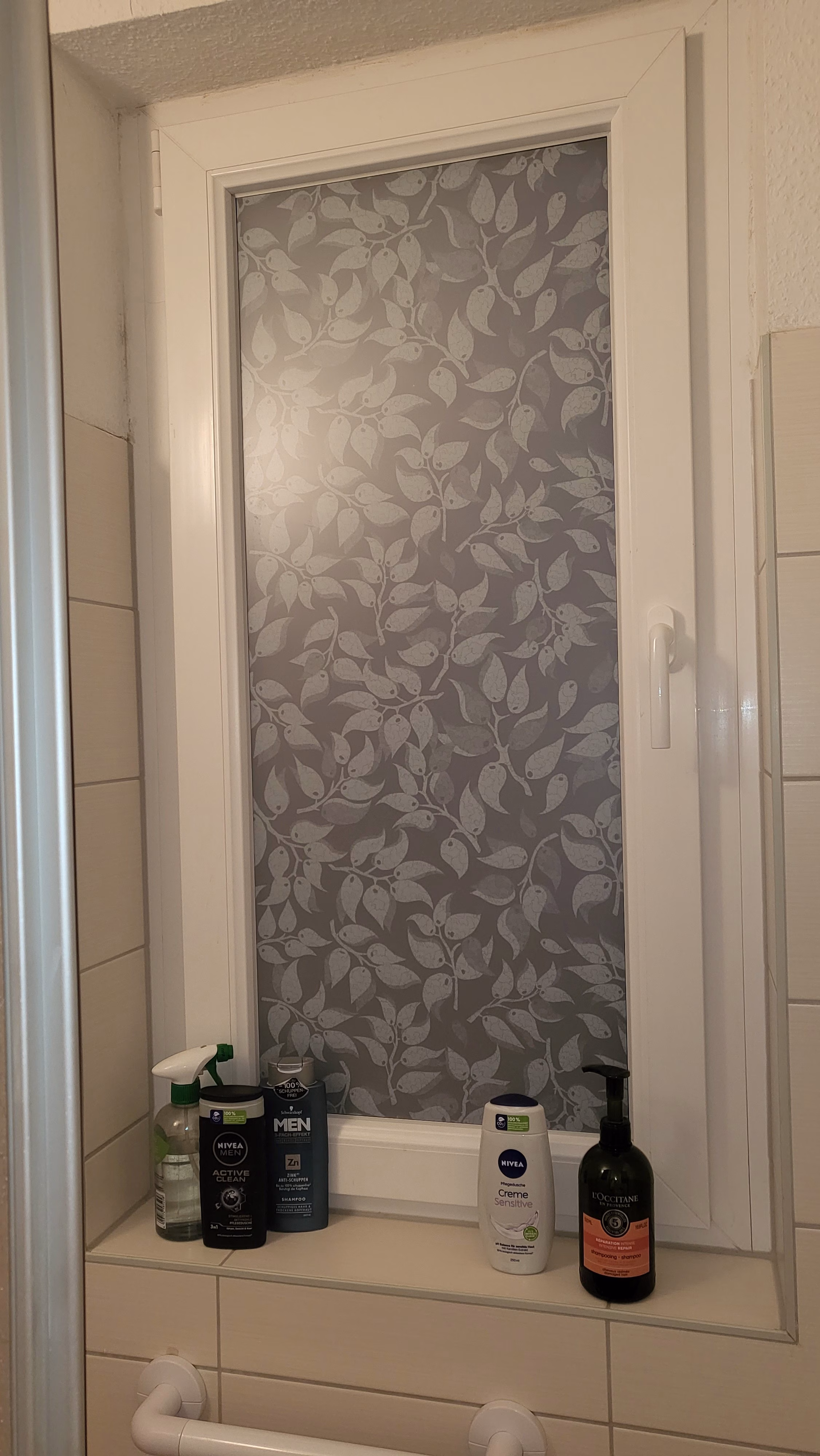 Fensterfolie mit weißen Blättern im Badezimmer
