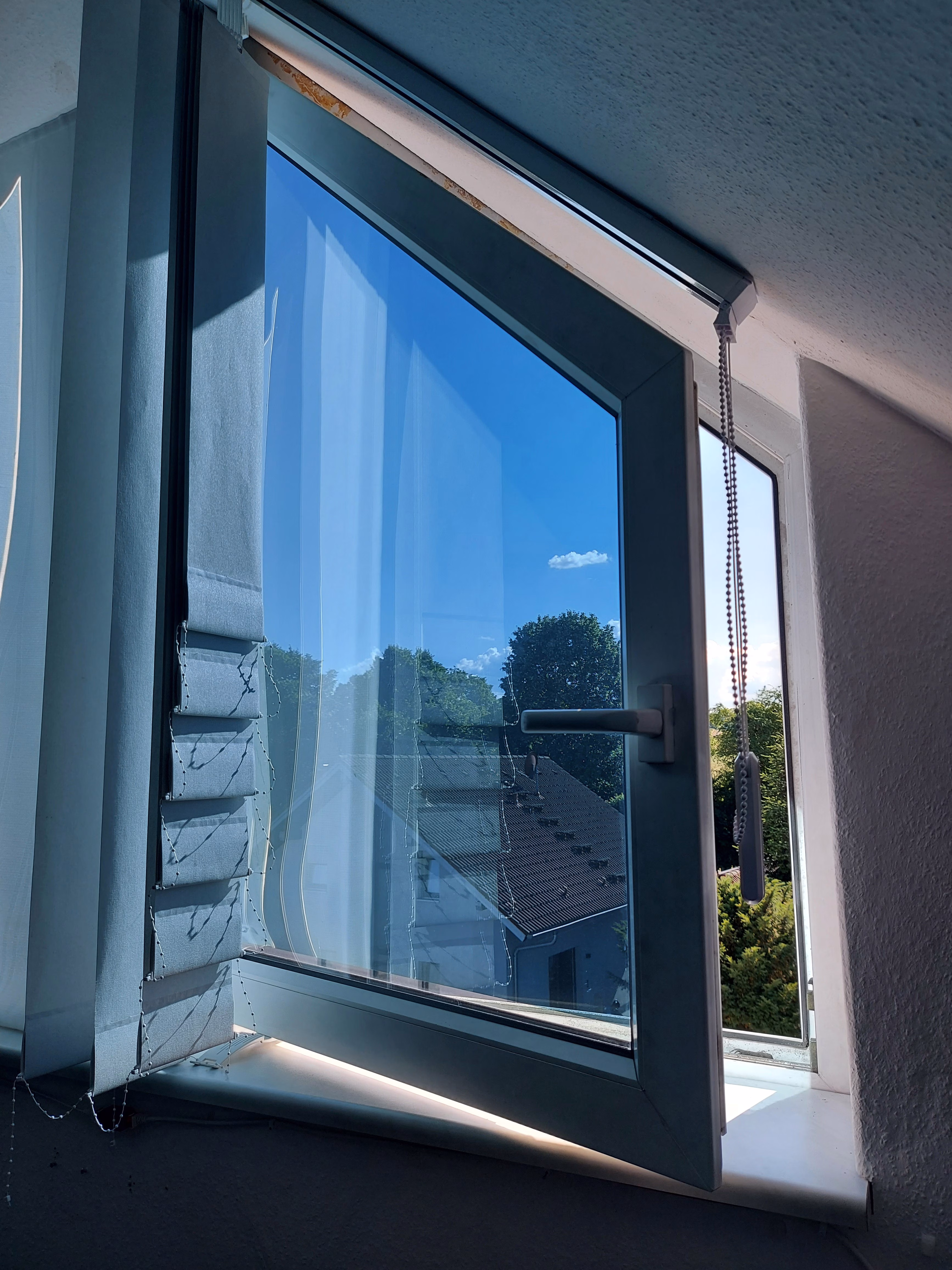 Sonnenschutzfolie silber blau verspiegelt an einem Fenster mit Schräge