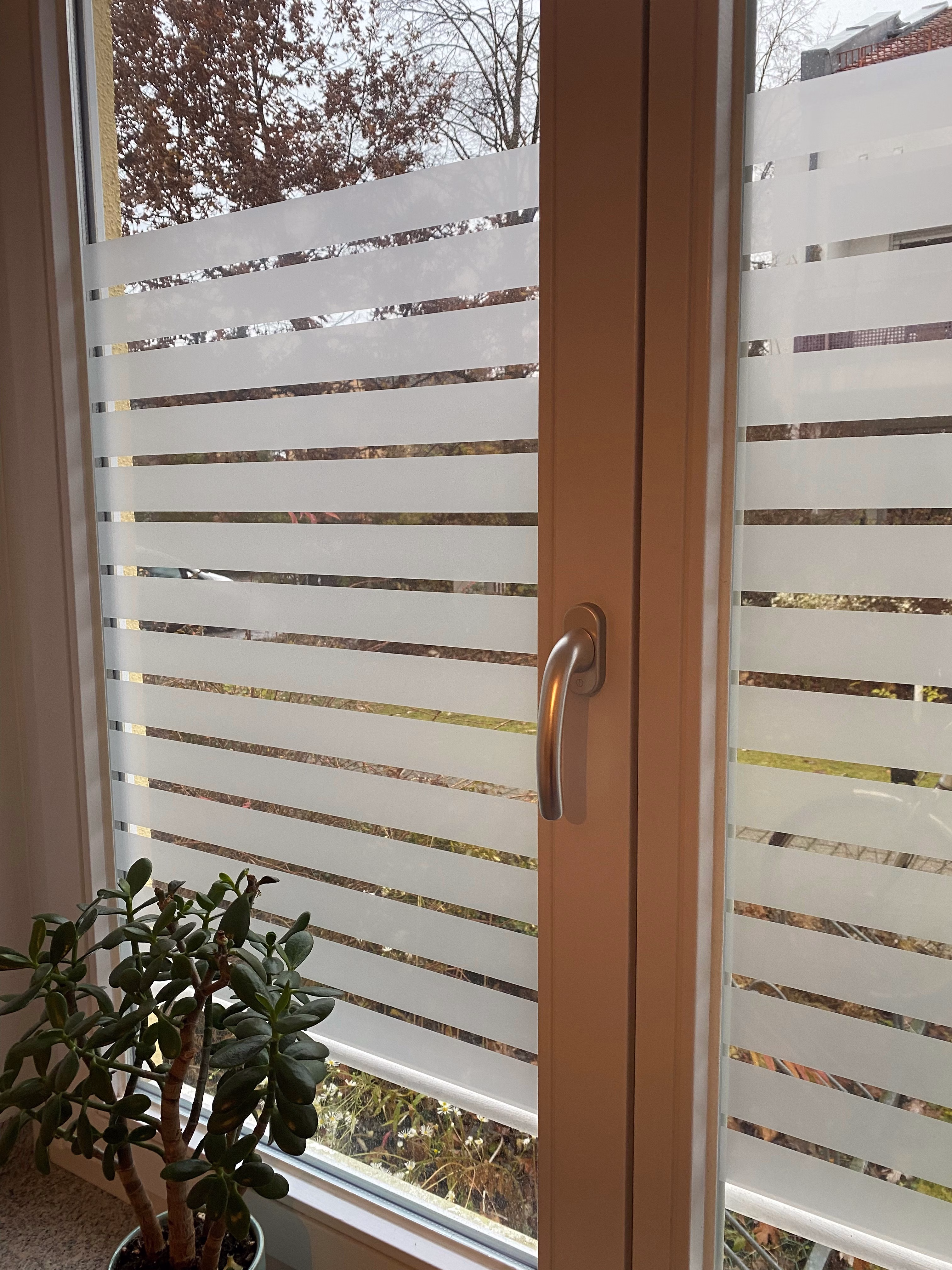 Sichtschutzfolie mit breiten weißen Streifen auf einem Fensterglas