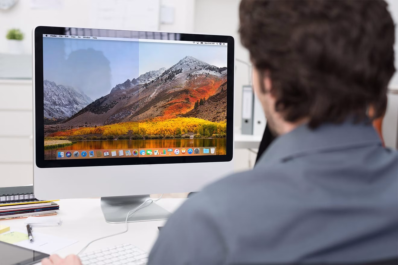 Mann schaut auf einen halb entspiegelten Monitor