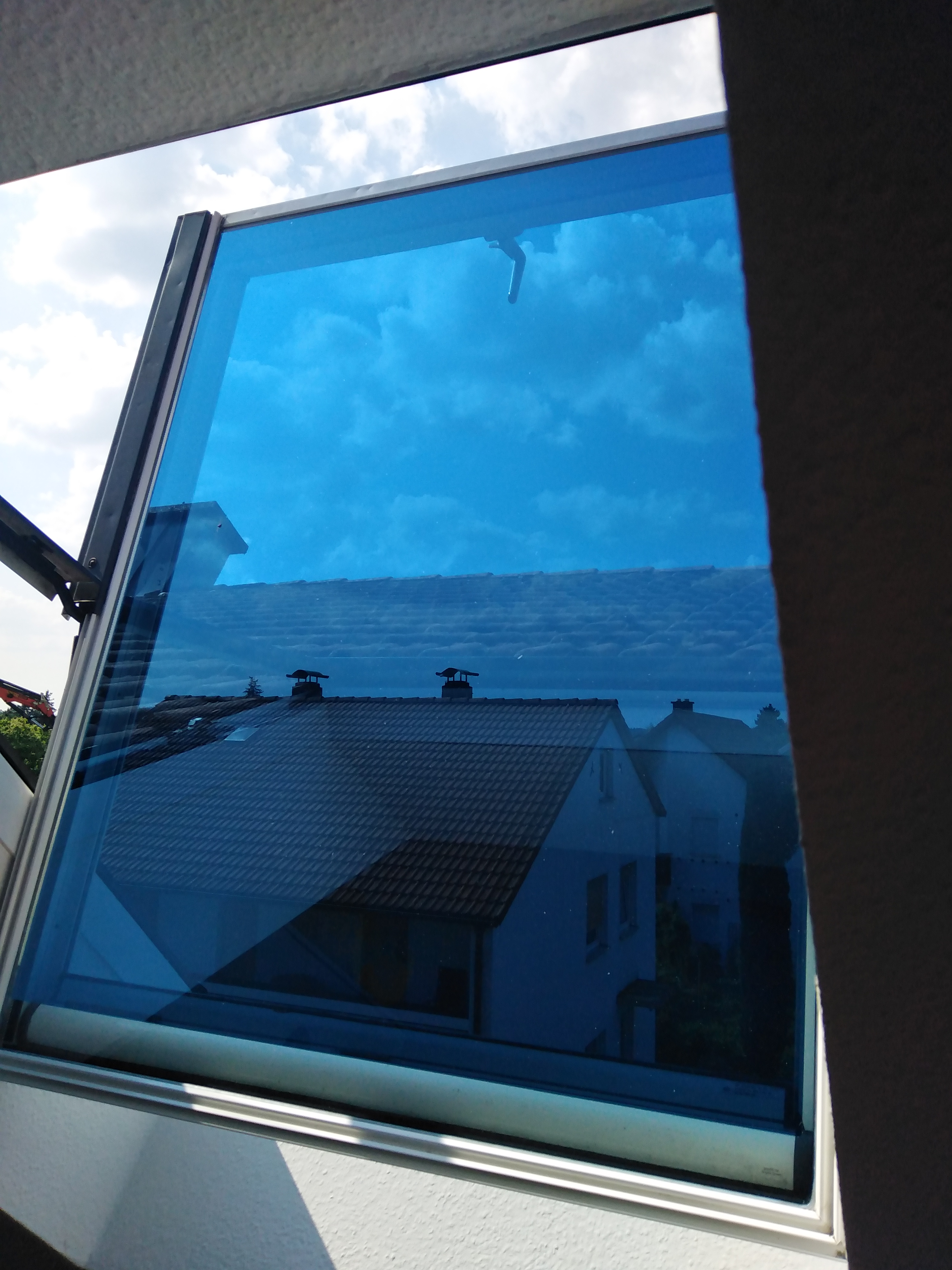 blau verspiegelte Sonnenschutzfolie auf einem Dachfenster