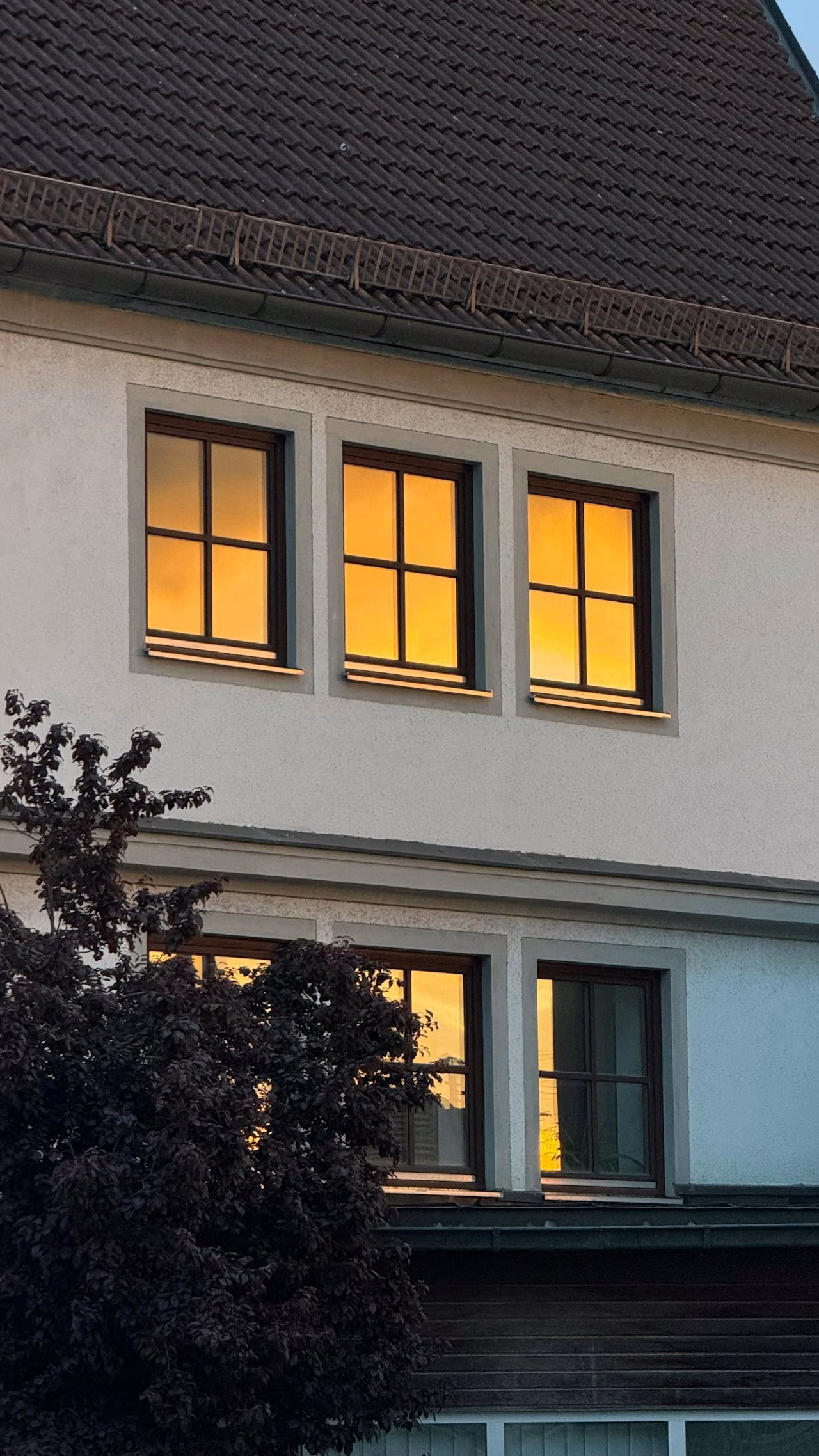 Wärmebelastung an Wohnhausfenstern Mehrere Fenster eines Wohnhauses mit starker Erwärmung durch Sonneneinstrahlung, ein möglicher Auslöser für thermische Spannungen im Glas.