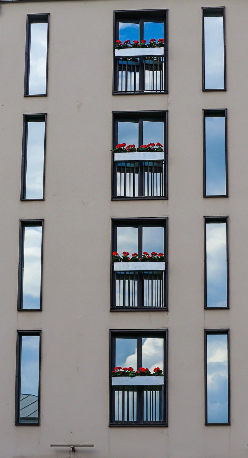 Moderne Fensterfolien können Sichtschutz und Sonnenschutz kombinieren und den Wärmeeintrag reduzieren. Moderne Wohnhausfassade mit Fenstern als Beispiel für Sonnenschutz- und Sichtschutzlösungen