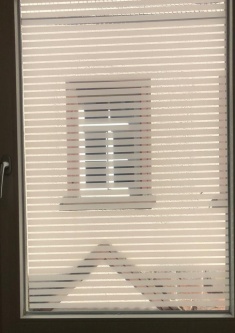 Dekorfolie mit transparenten Streifen aufgeklebt auf einem Fensterglas