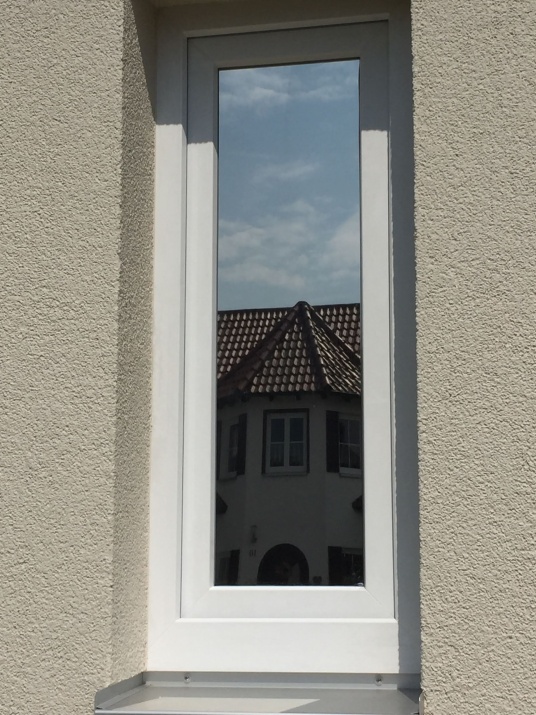 Sonnenschutzfolie silber dunkel verspiegelt auf einem schmalen Fenster mit Außenansicht